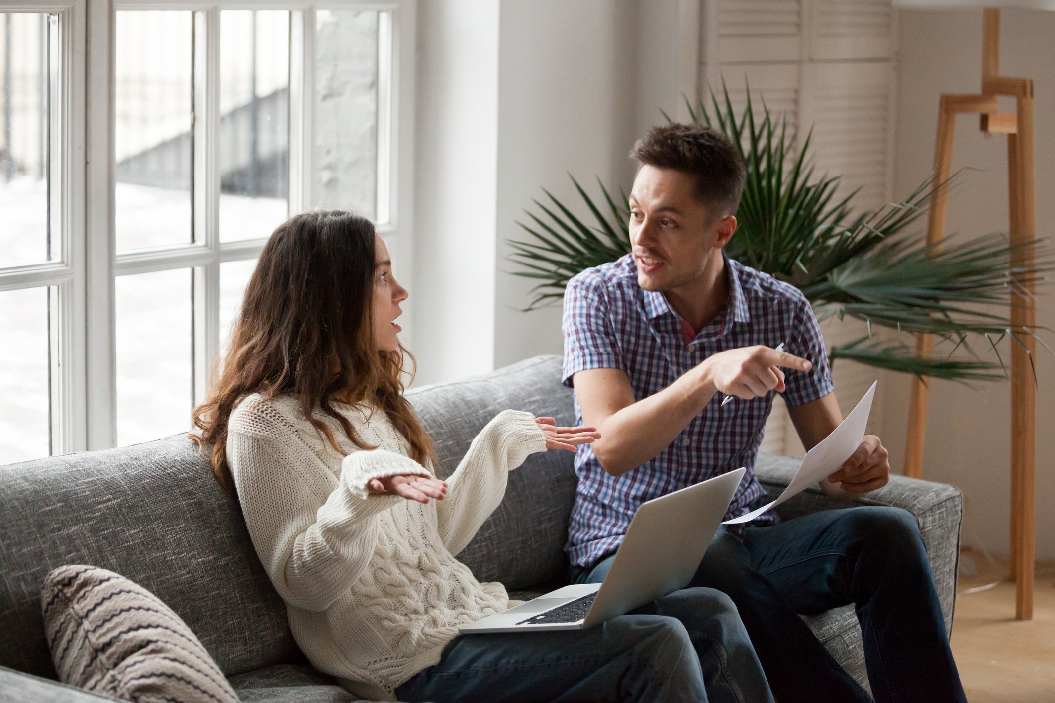 Couple discussing finances in the living room.