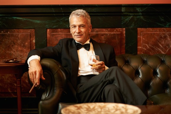 Debonair person sitting in lounge with cigar.