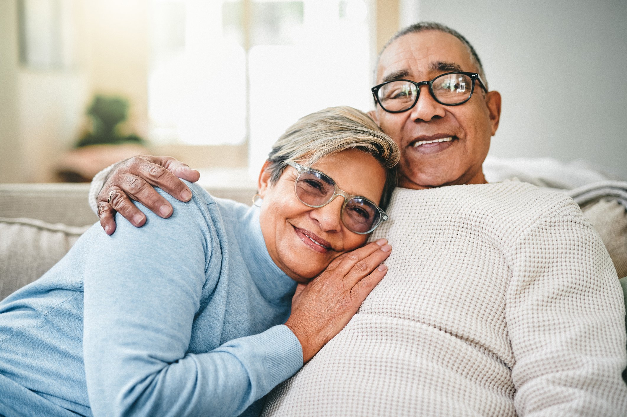 Two smiling people sitting together on a couch.