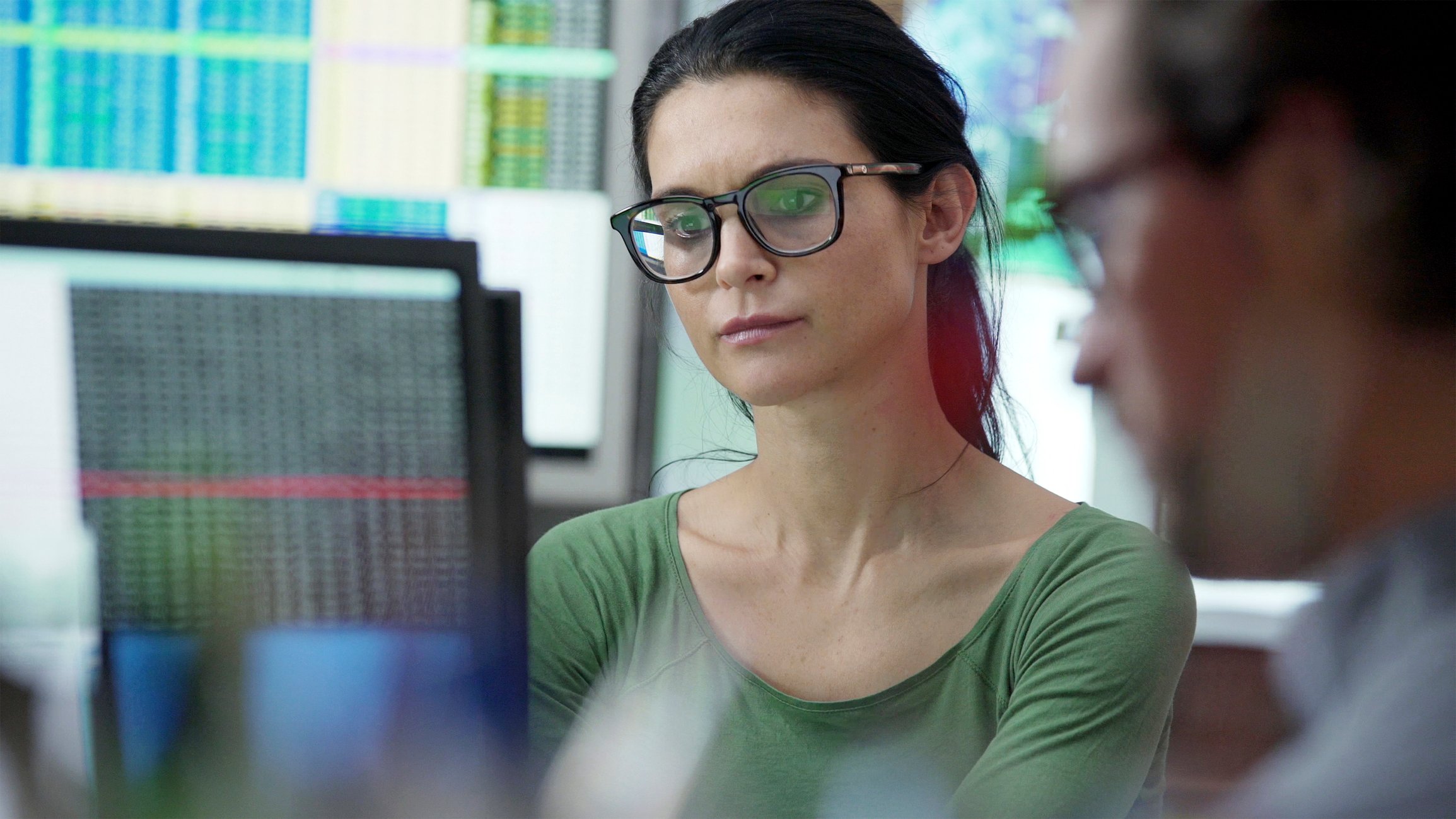 Two business people looking at data on screens. 