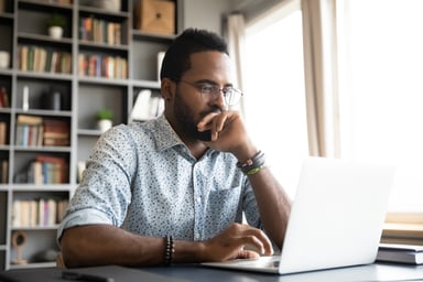 Man with skeptical expression looking at laptop