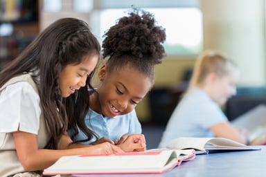 two school kids reading a book.