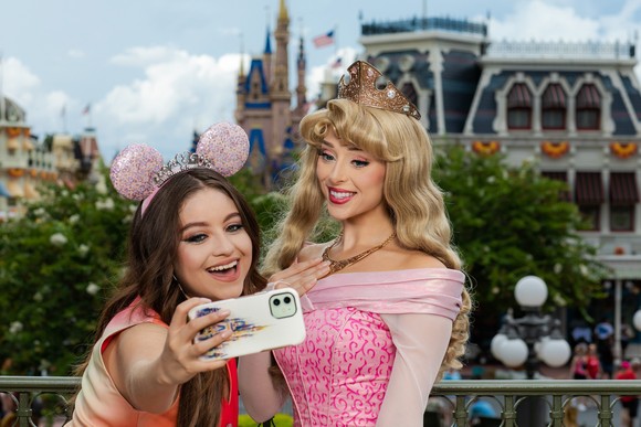 Karol Sevilla taking a selfie with Princess Aurora overlooking Main Street U.S.A. at Disney World's Magic Kingdom.