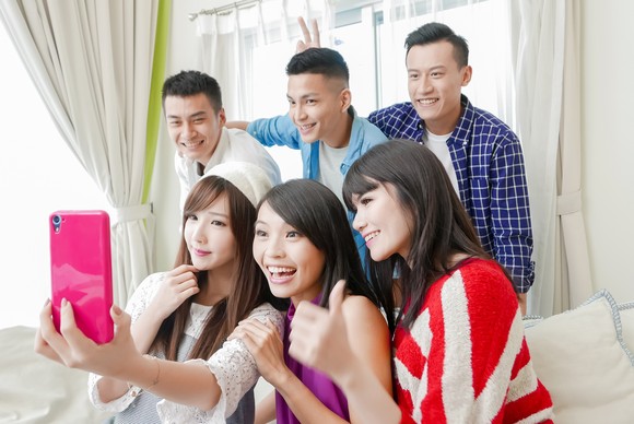 A group of six friends take a selfie with a phone.