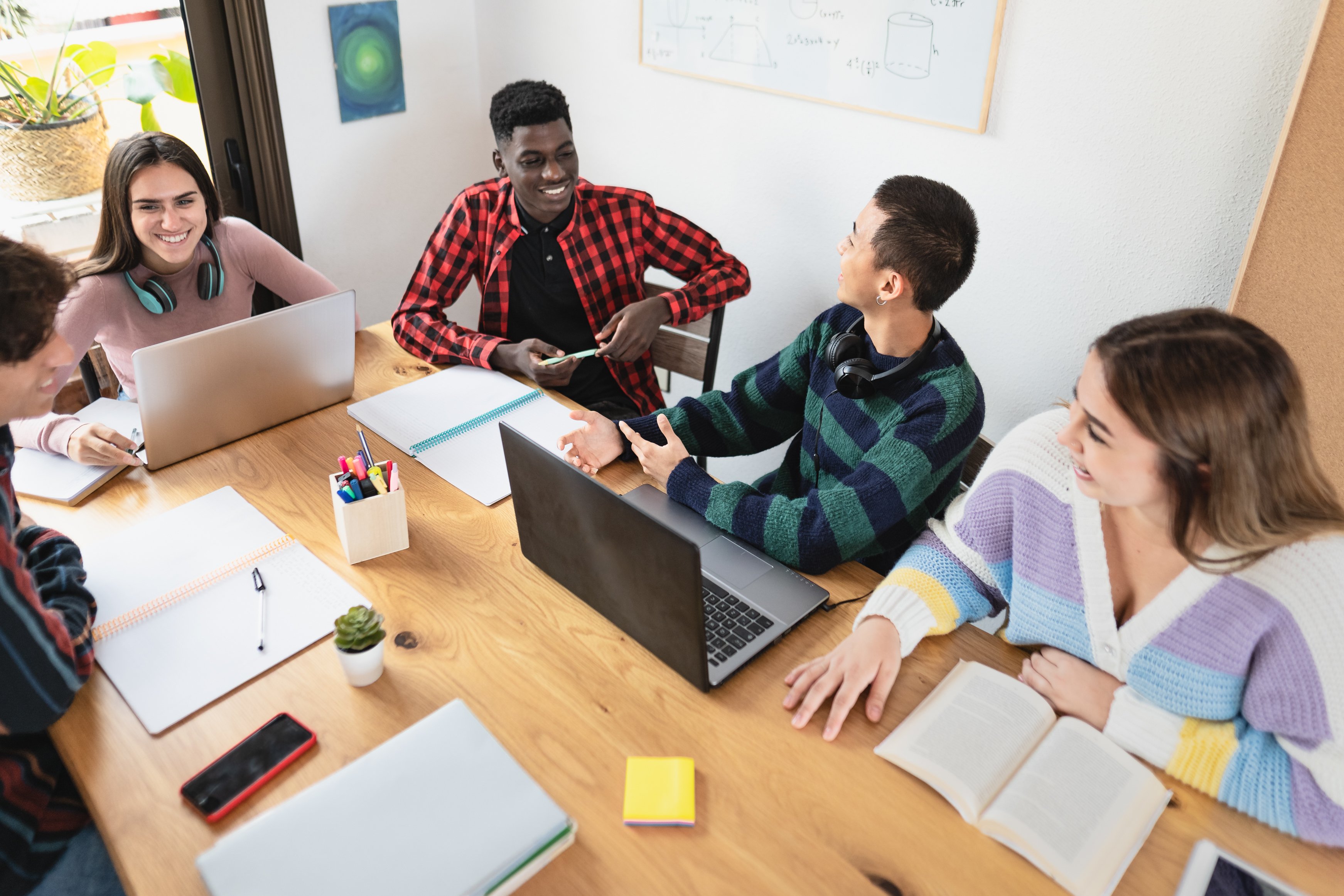 A group of young people sitting at a table with laptops and financial documents.