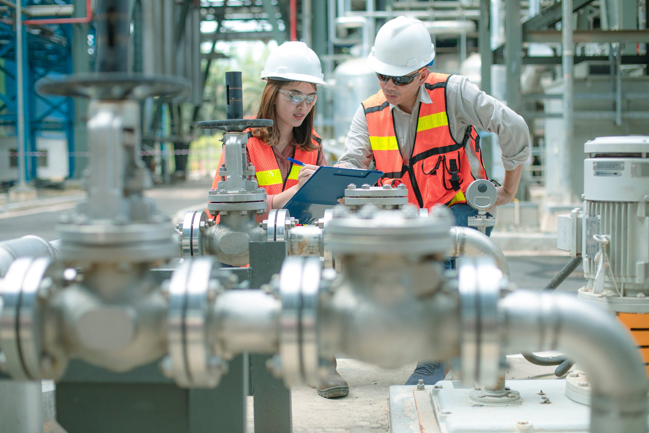 Two workers wearing personal protective equipment at an industrial site.