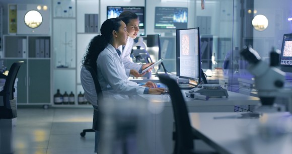 Life science researchers in a laboratory reviewing data on a computer together.