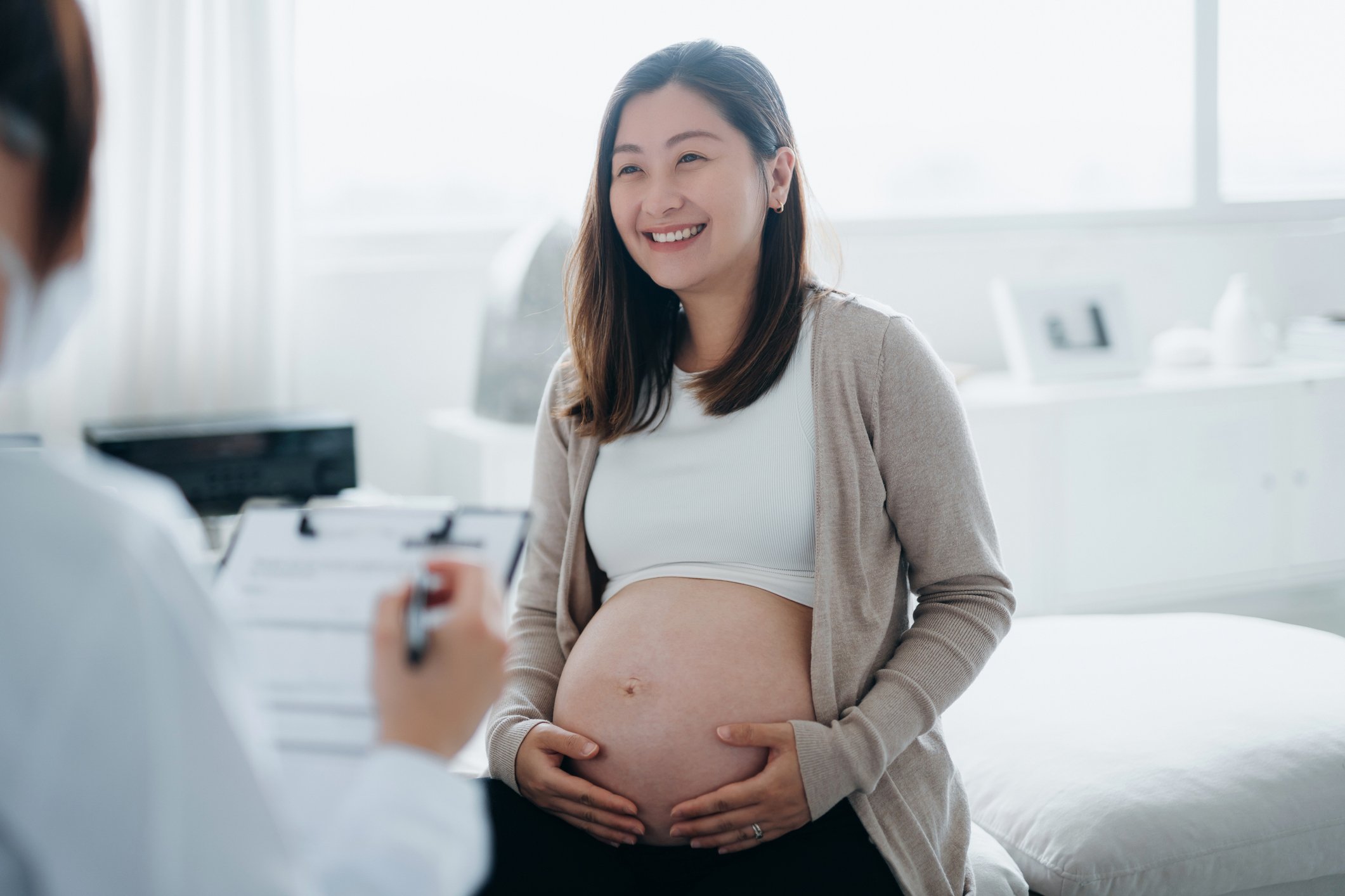 Smiling pregnant patient meeting with doctor.