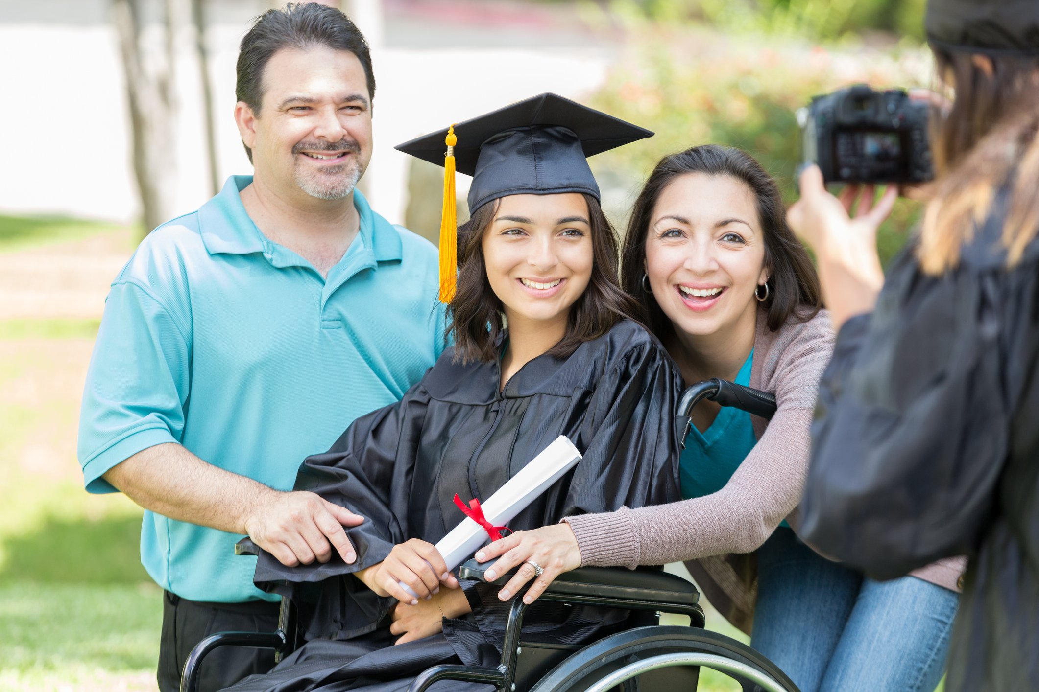 Smiling parents taking photo with college graduate.