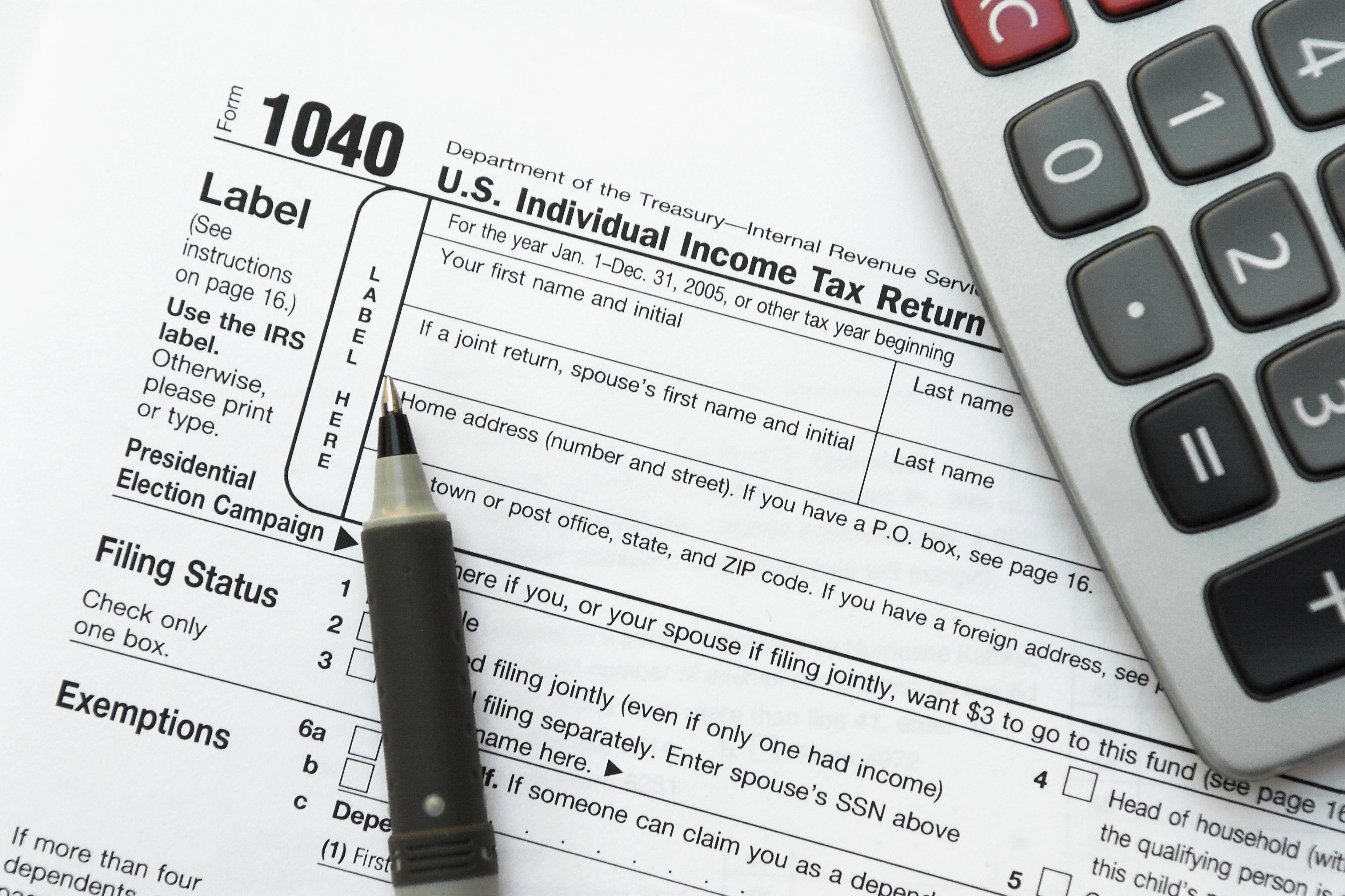 A closeup on form 1040 with a pen and calculator.