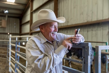 person wearing cowboy hat smiling in barn