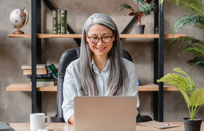 Smiling person typing on laptop in office.