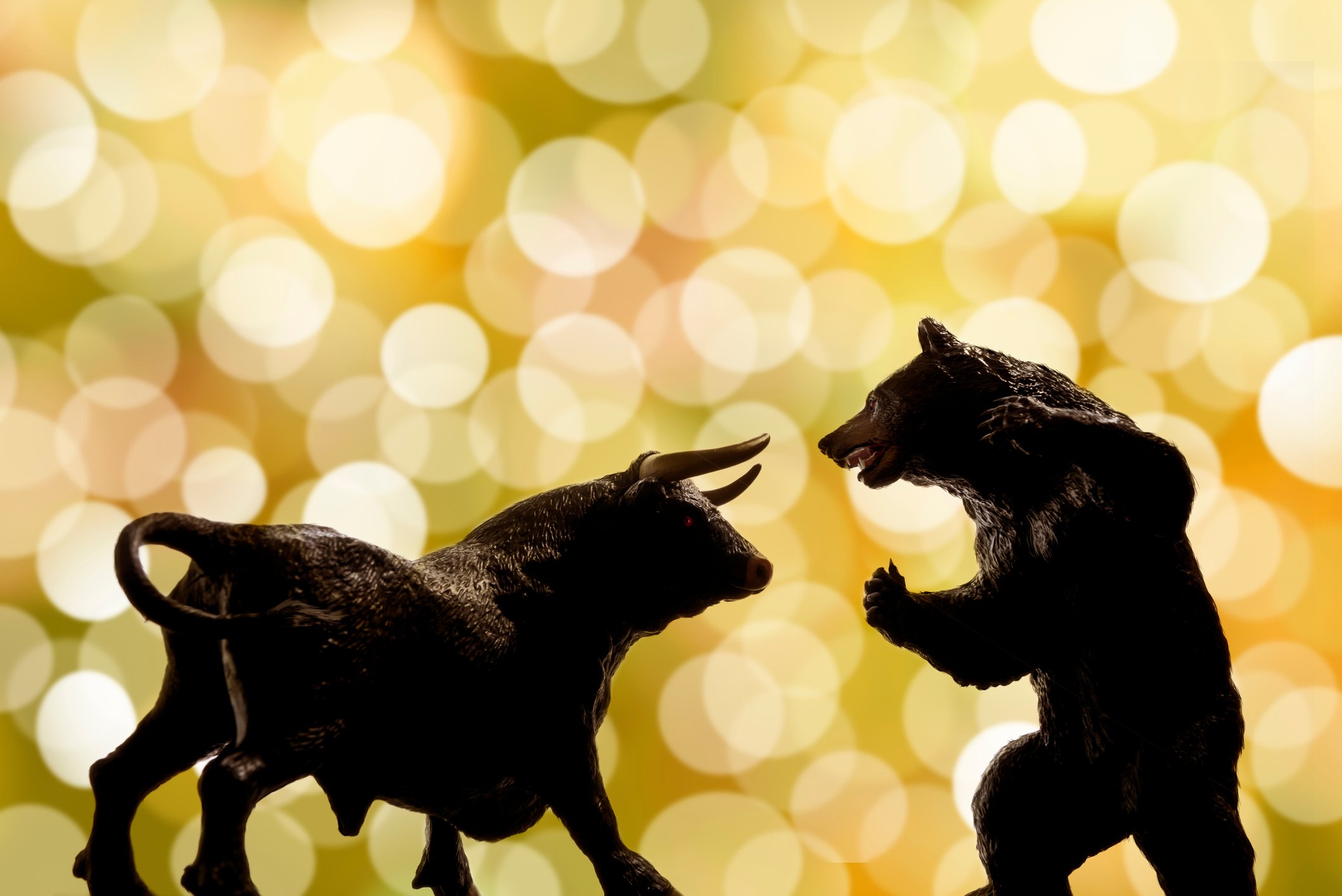 A bull figurine facing a bear figurine.