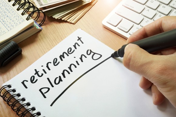 The words retirement planning written in black marker on a blank white page of a notebook.