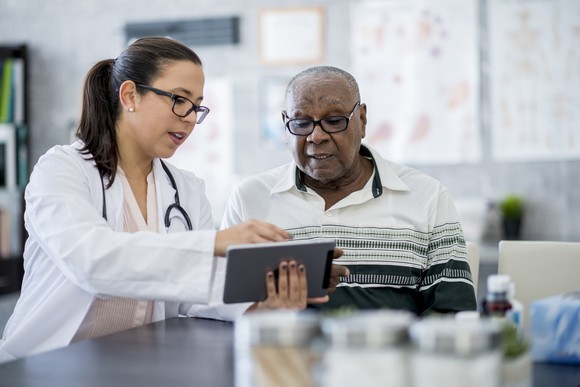 Doctor pointing to a tablet and talking to a patient in a clinic.