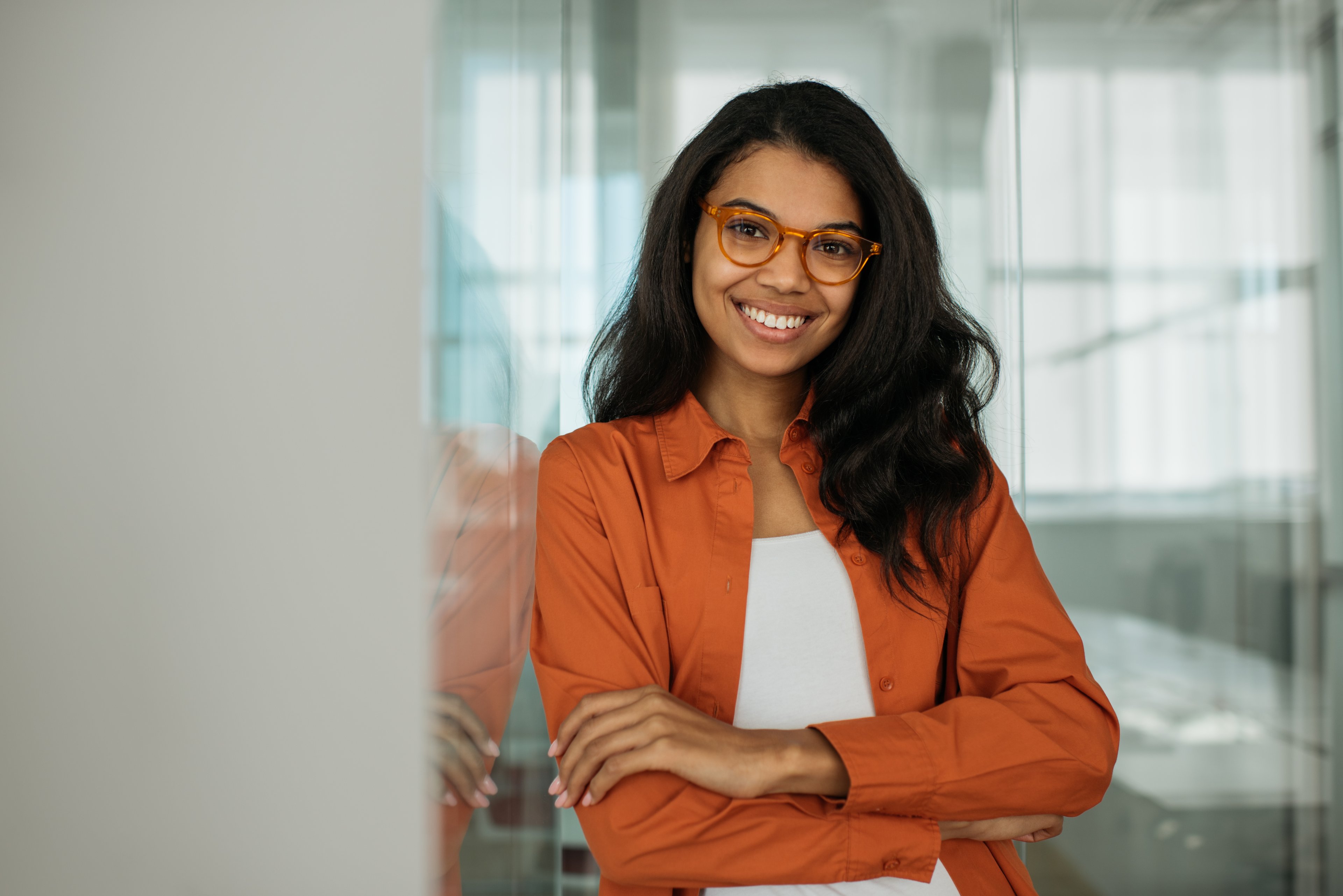 Person wearing glases smiling in front of a window.