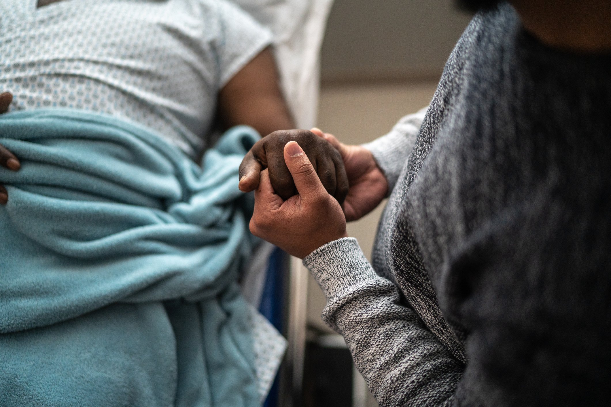 Son holding father's hand at the hospital 