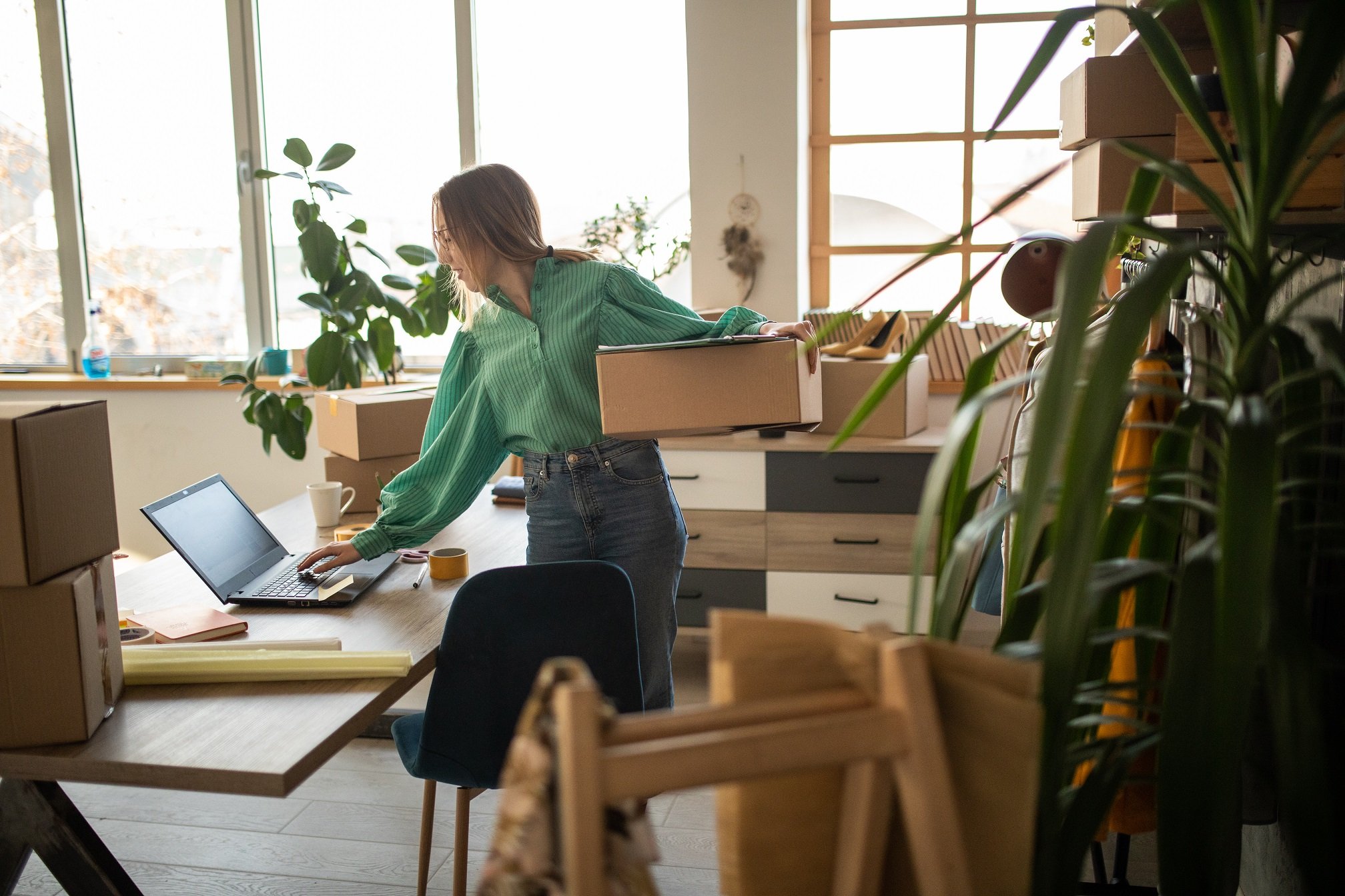 A person holding a box and looking at a computer.