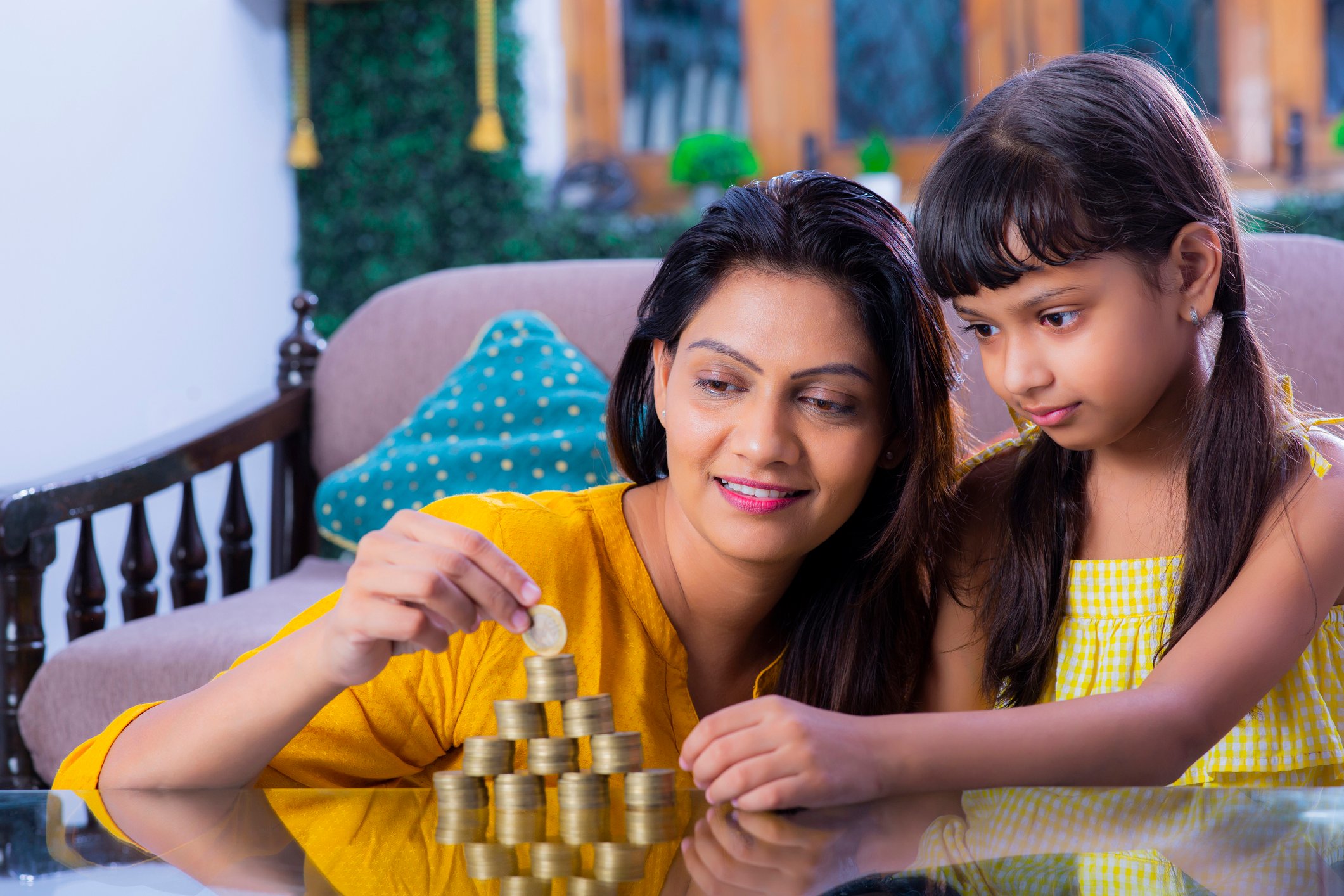 An adult and a child stacking coins in a family room. 