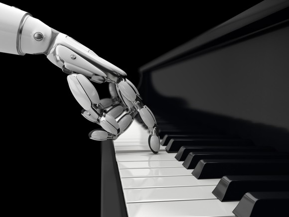A robot hand presses an E key on a piano keyboard. 
