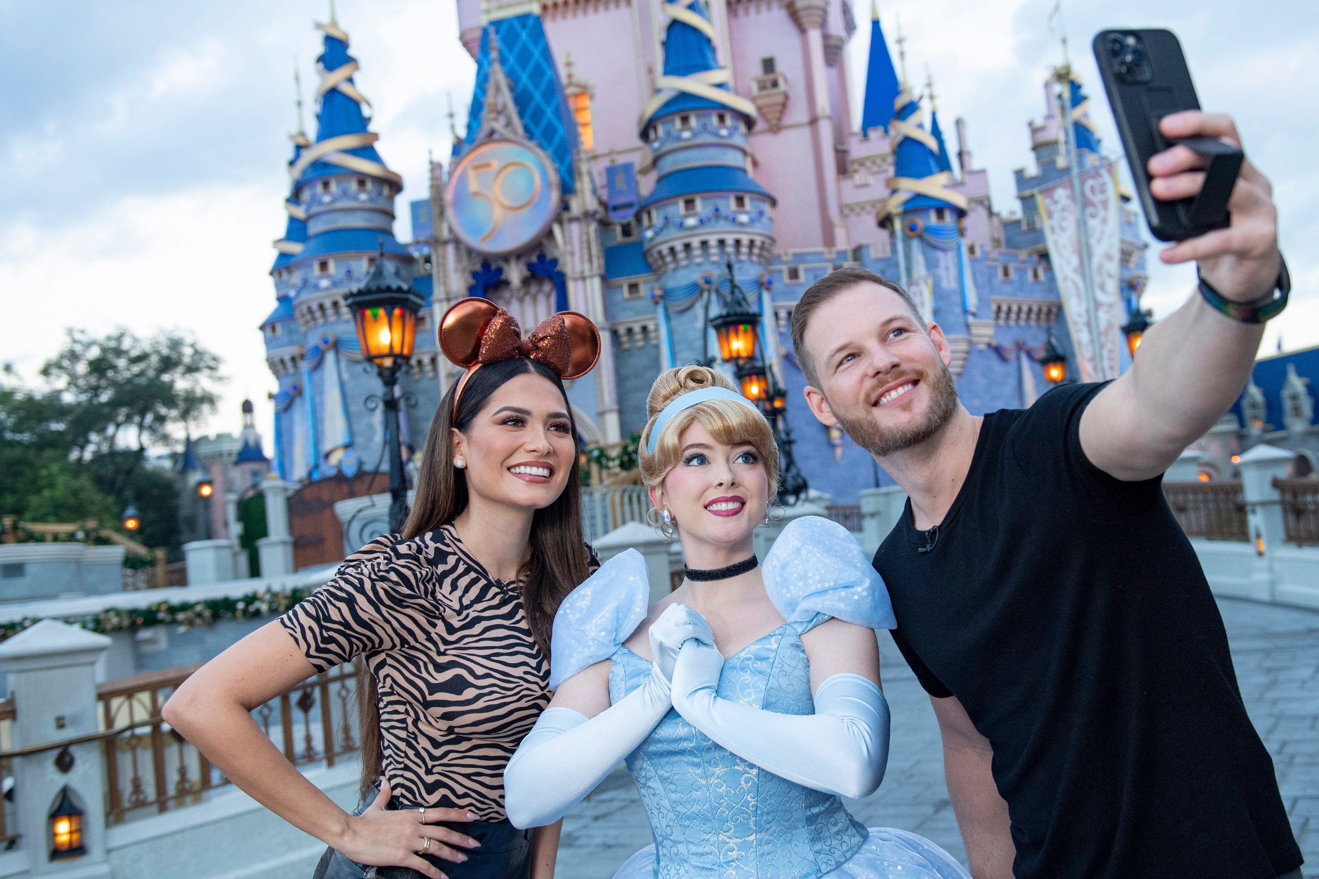 Cinderella posing with guests at Disney World's Magic Kingdom.