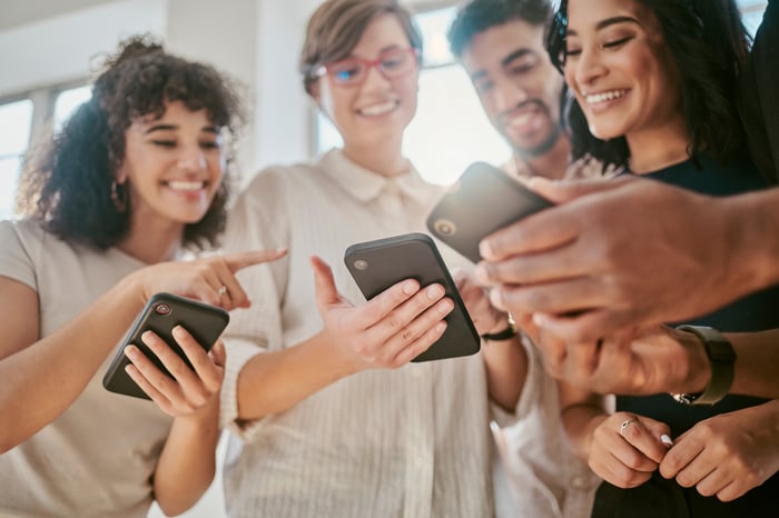 People smile while looking at cell phones.