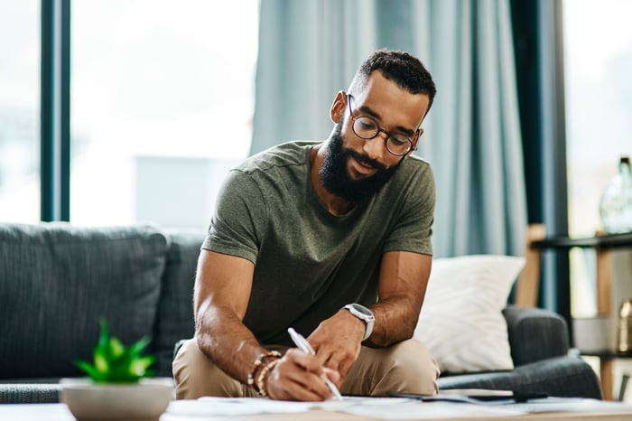 Person sitting on a couch looking at documents.