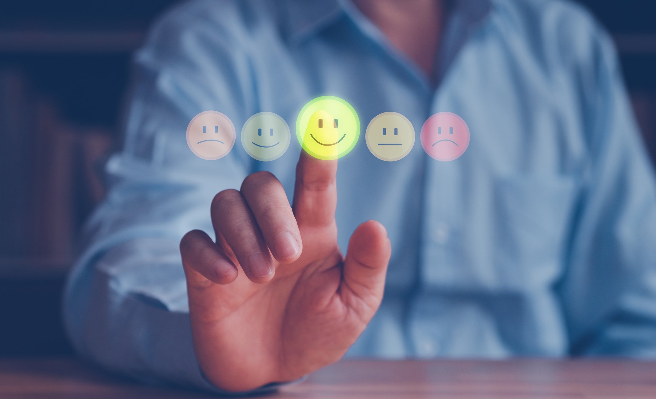 A person pointing to an icon showing a smiley face next to other emoji icons.