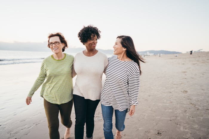 Three people smiling and walking on the beach.