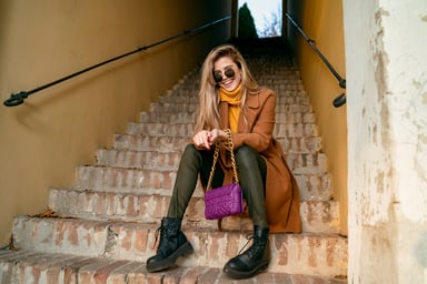 Person sitting on steps in fashion apparel.