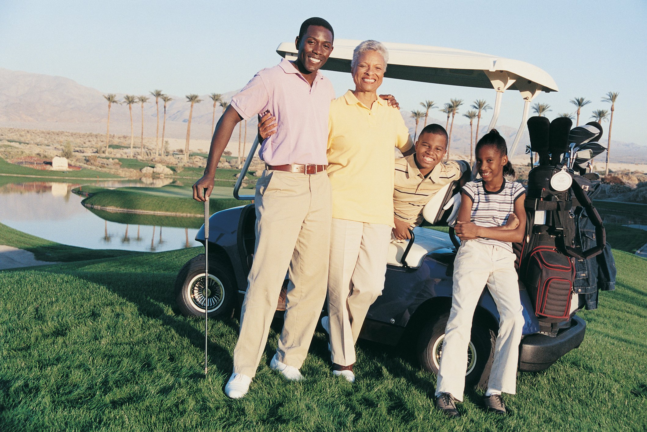 A family posing on a golf course in their golf kart.