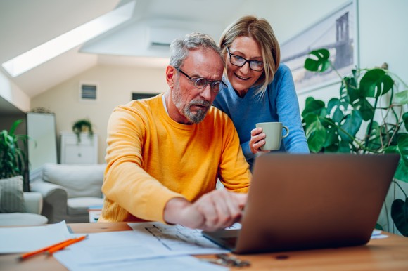 Two people looking at laptop in living room.