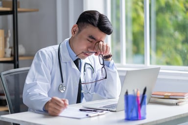 tired doctor doing paperwork at desk