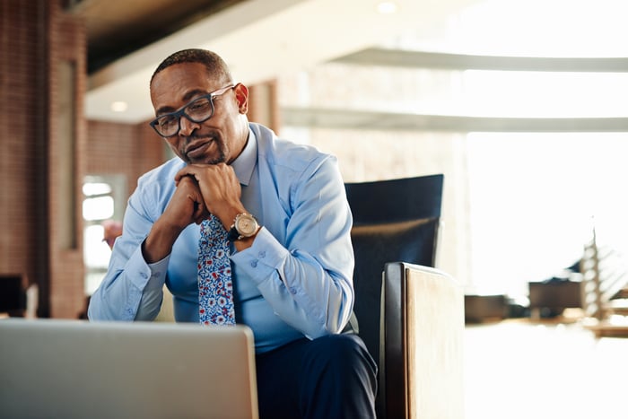 Someone sitting in a chair looking at a laptop.