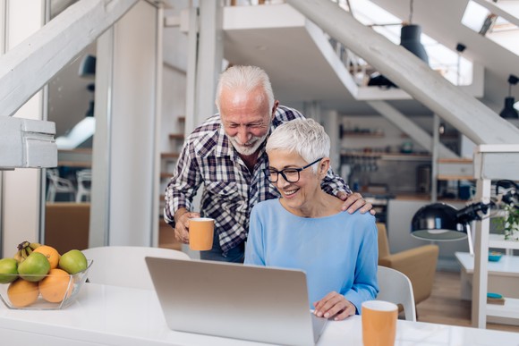 Two people looking at a laptop in a home setting.