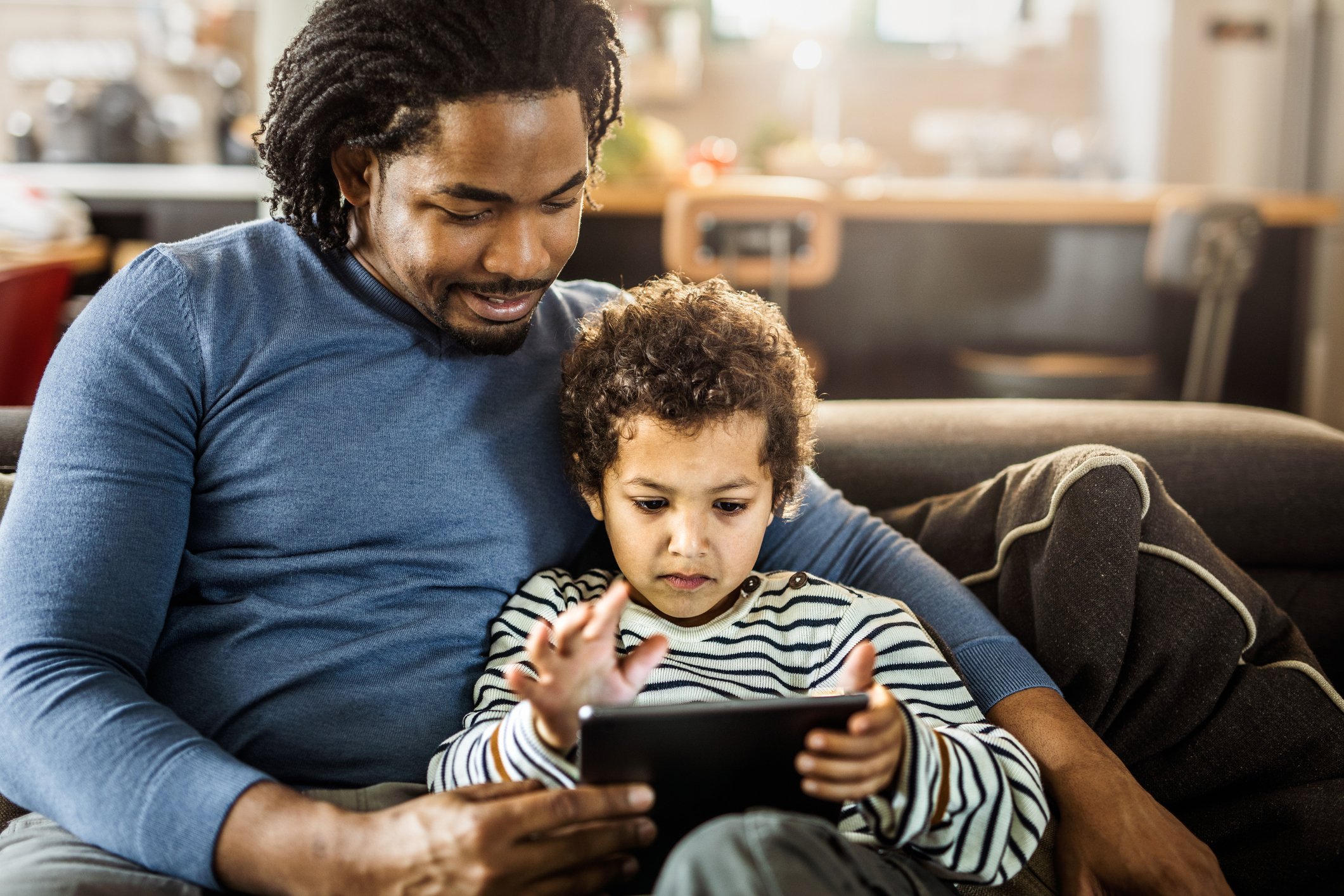 An adult and child look at a tablet.