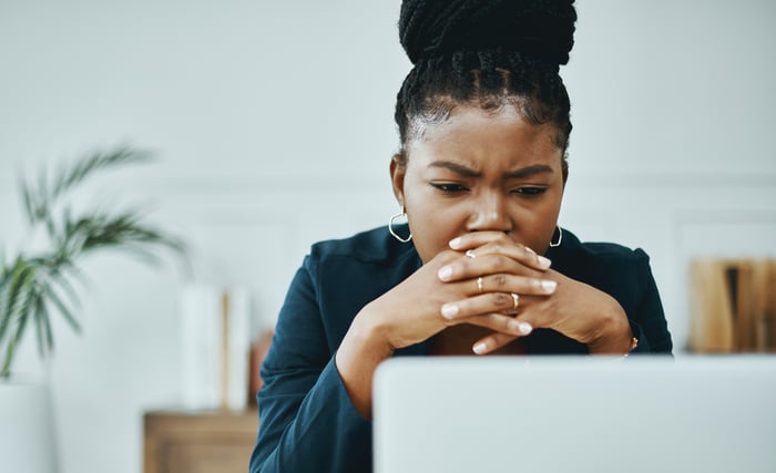 A person looks worried while staring at their laptop.