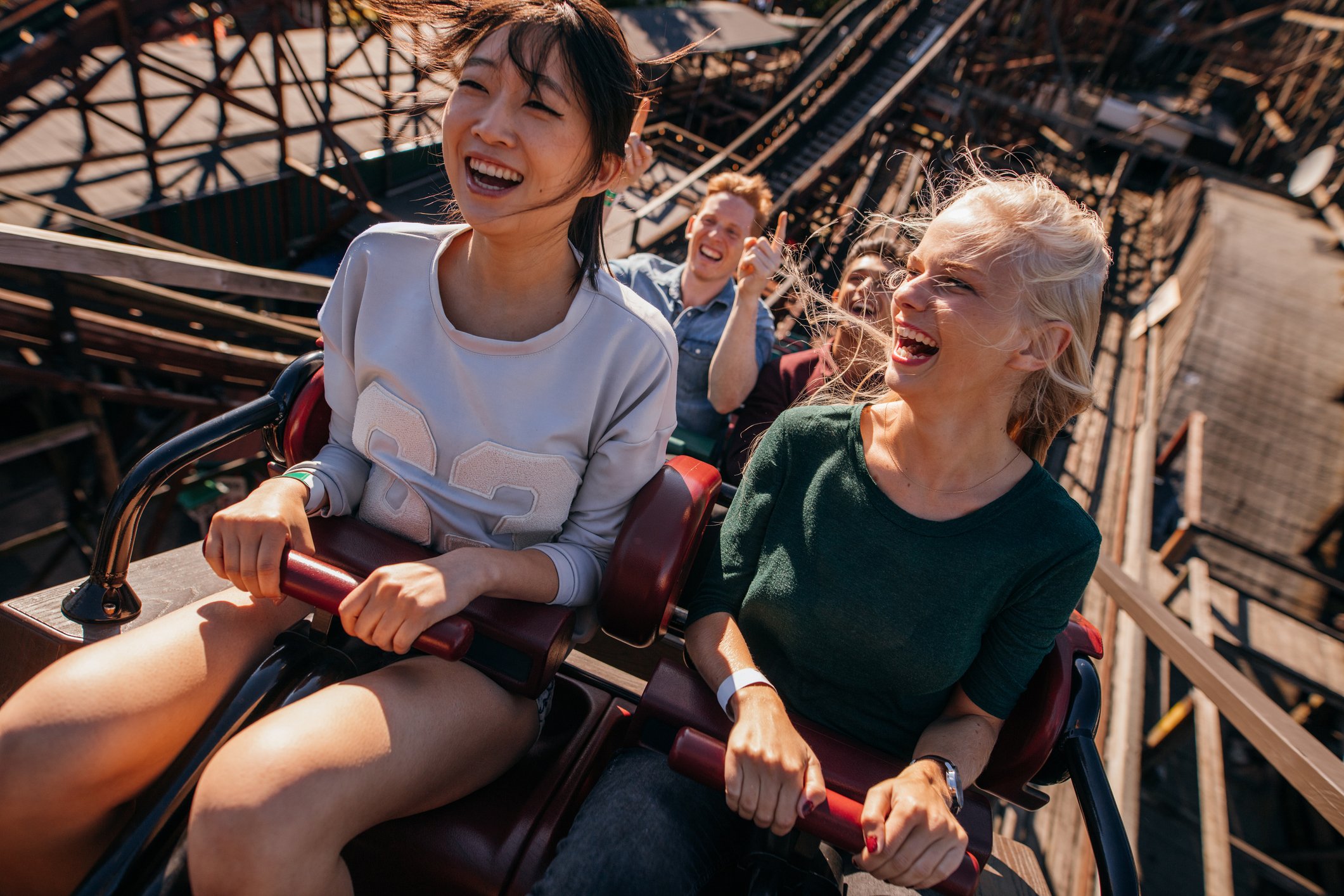 Two people sitting in the front of a rollercoaster as it climbs up a hill.