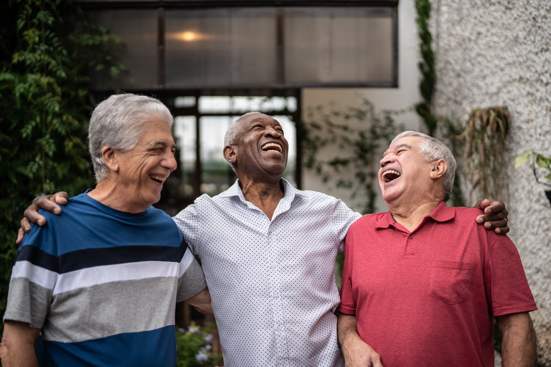 Three seniors laughing with their arms around each others' shoulders.