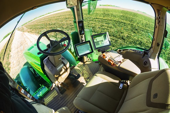 The cockpit of a Deere tractor is seen, including screens used in automation or the tractor's operation
