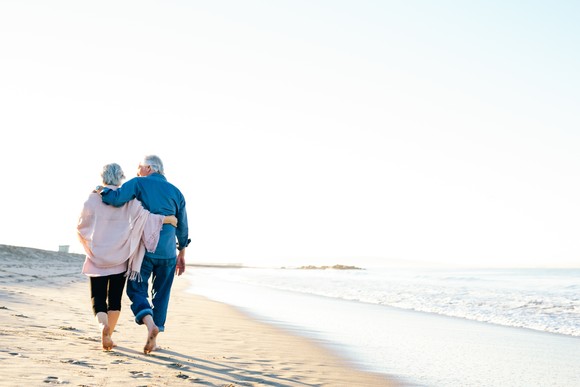 Two people hugging and walking on the beach.