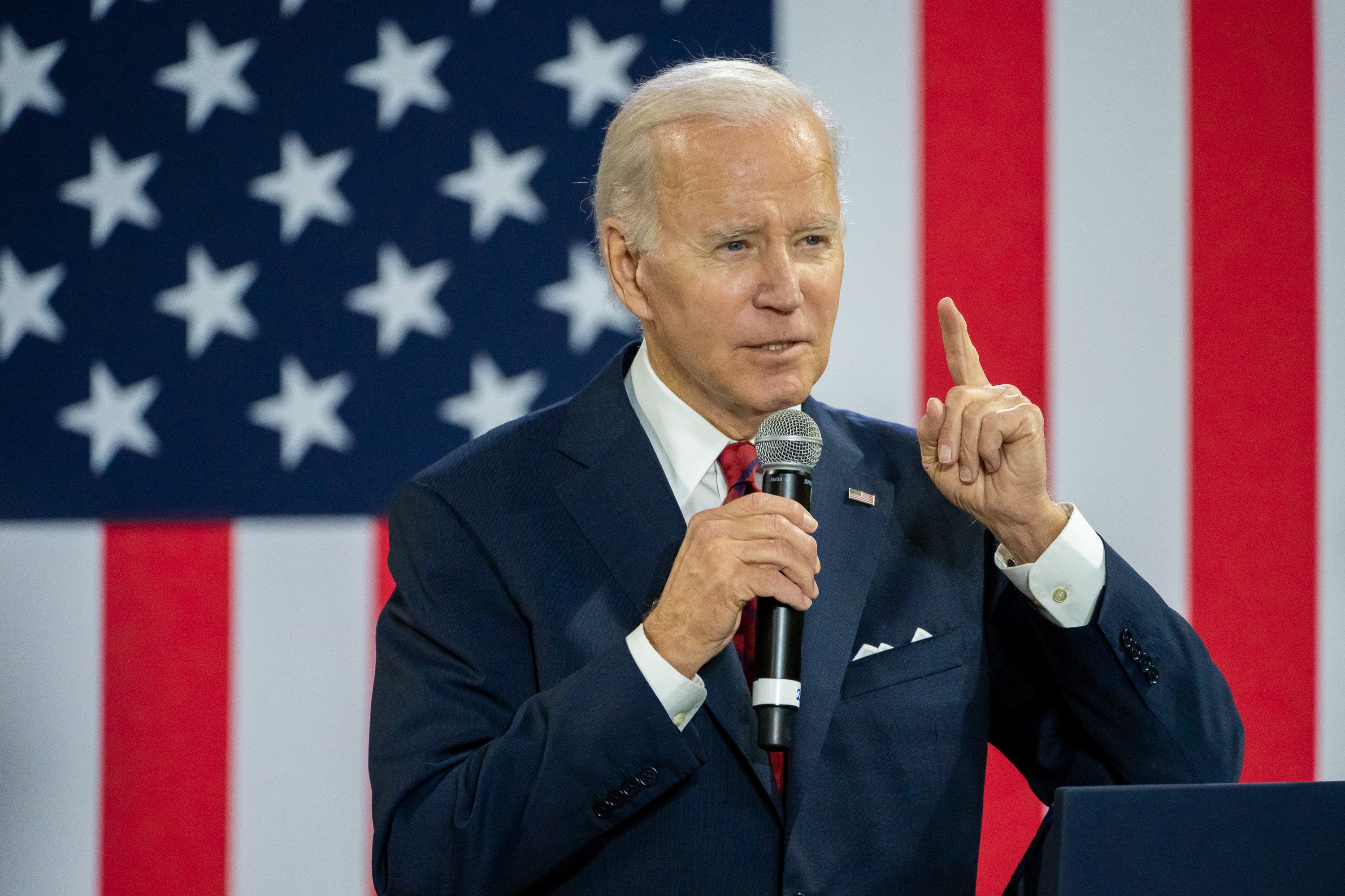 Joe Biden delivering remarks in front of an oversized American flag.
