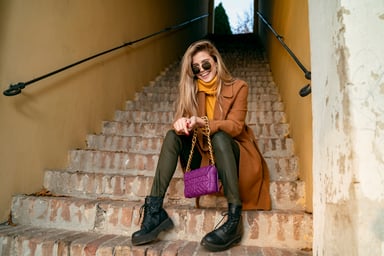 Person sitting on steps in fashion apparel.