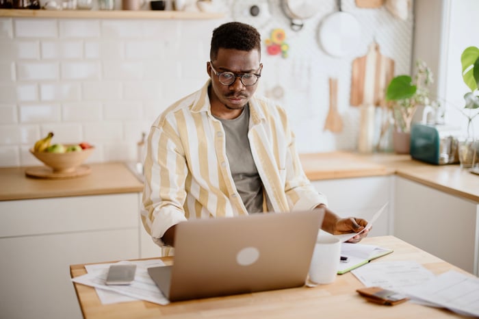 Person looking at laptop in kitchen. 