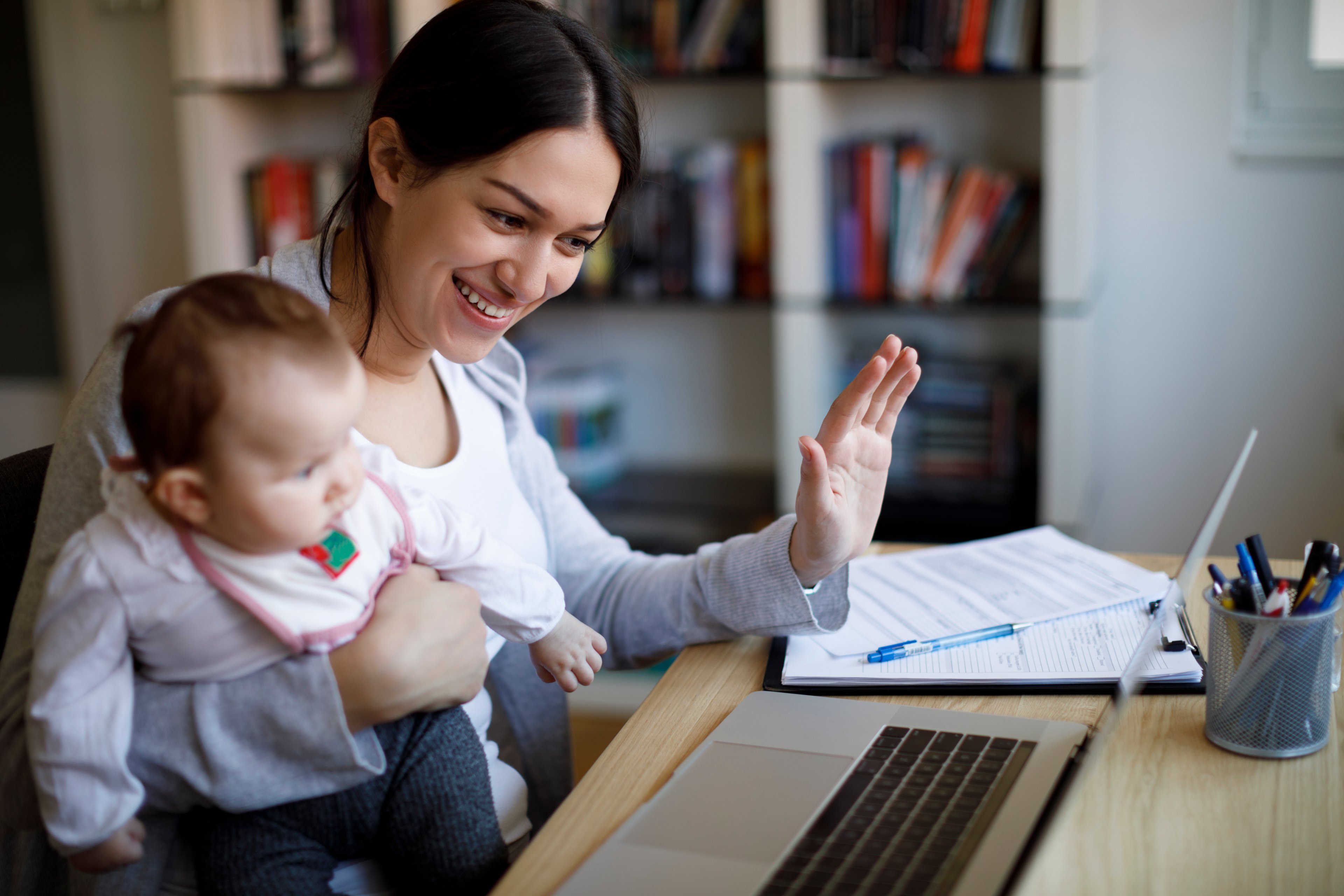 Person at laptop holding baby.