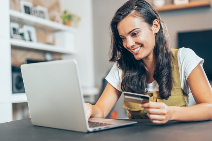 A person shops online while holding a credit card.