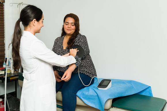 Doctor checking patient's blood pressure.