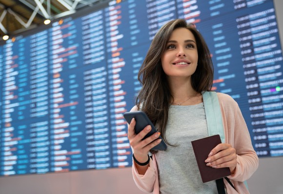 A traveller in front of a flight departures board.