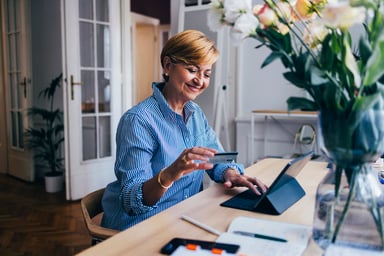 A person sitting at a computer with a credit card