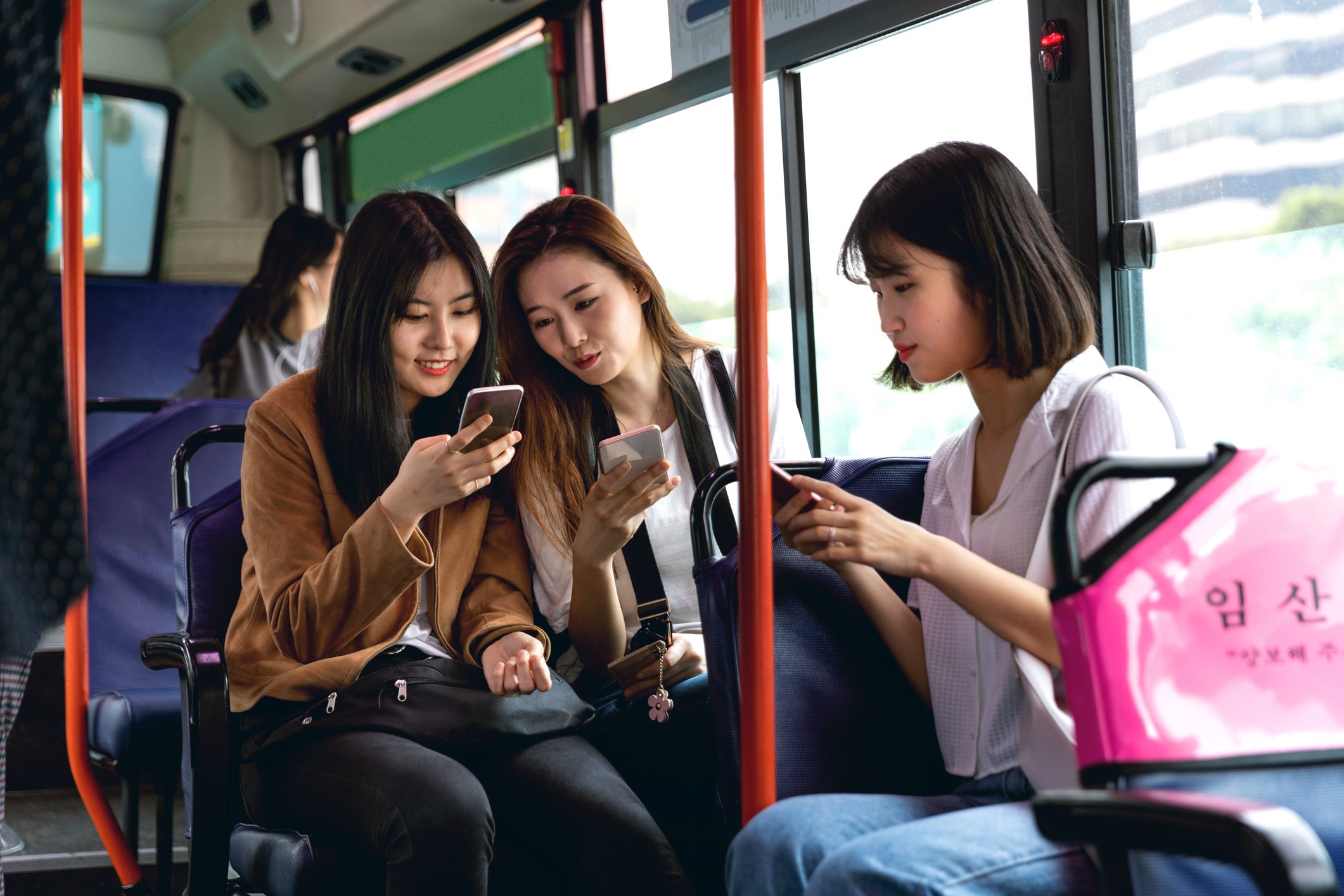 People on a bus looking at each other's smartphones.